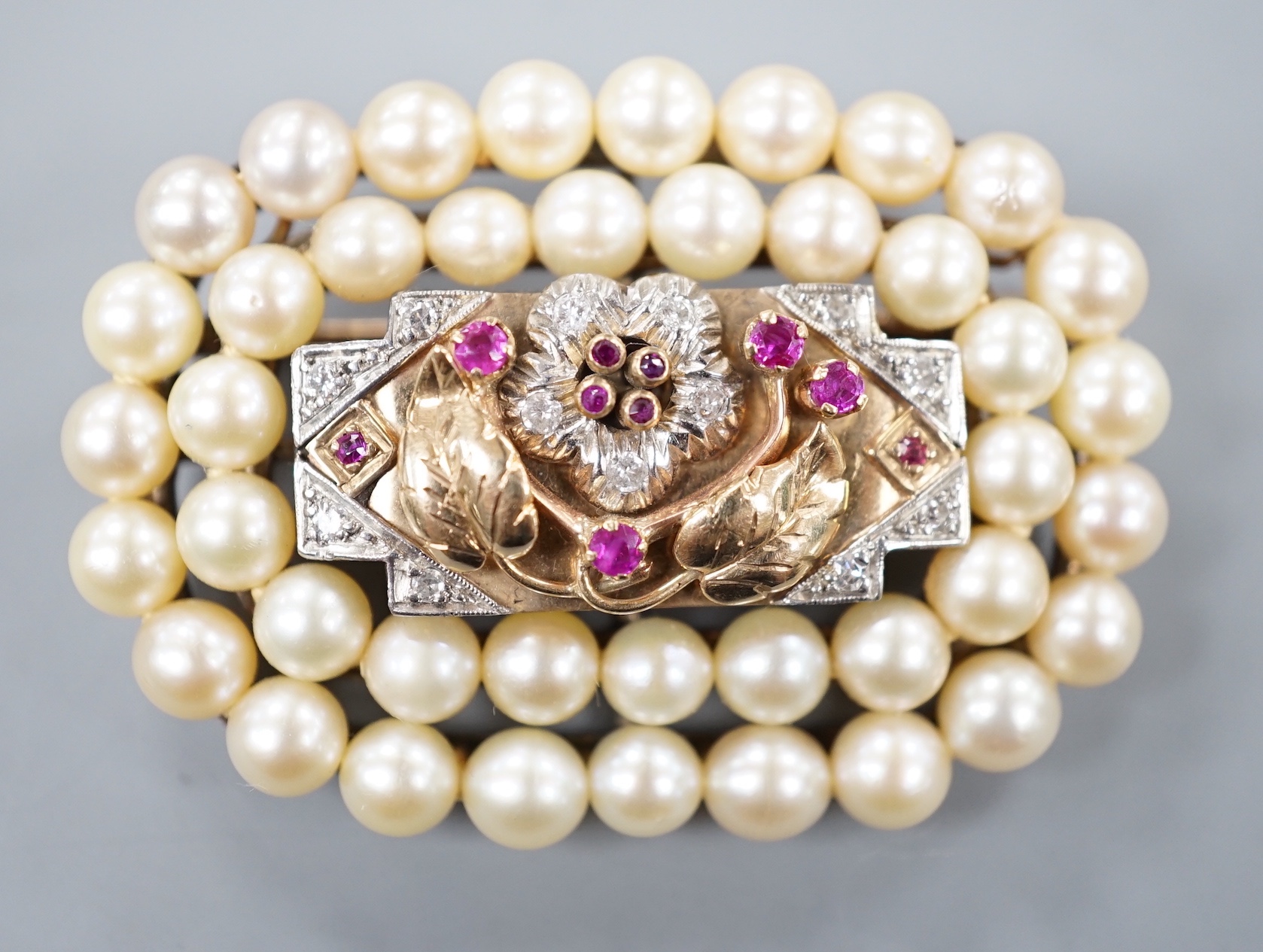 A yellow and white metal, ruby, diamond and cultured pearl cluster set oval brooch, 51mm, gross weight 31.1 grams.